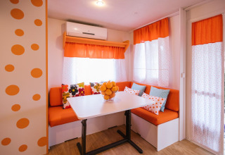 Kleurrijke eethoek in Miramar Mobile home CINQUE TERRE, Spanje, met oranje accenten en stippenpatroon.