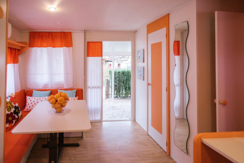 Interieur van Miramar Mobile home CINQUE TERRE in Spanje met oranje gordijnen en witte eettafel.
