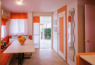 Interieur van Miramar Mobile home CINQUE TERRE in Spanje met oranje gordijnen en witte eettafel.