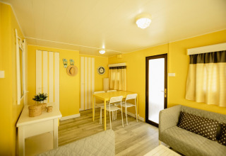 Lichte, gezellige woonkamer in de Miramar Mobile home CINQUE TERRE met gele muren en eethoek.