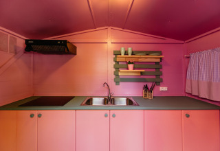 Kleurrijke mobiele huis keuken met roze kasten, dubbele gootsteen en open planken in Miramar Mobile Home.