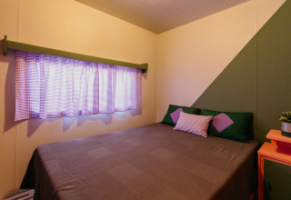 Slaapkamer in Miramar Mobile home CINQUE TERRE in Spanje met tweepersoonsbed en gekleurde kussens.