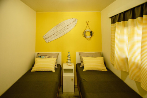 Kamer met twee eenpersoonsbedden in Miramar Mobile Home CINQUE TERRE, Spanje, gele muur, stranddecoratie.