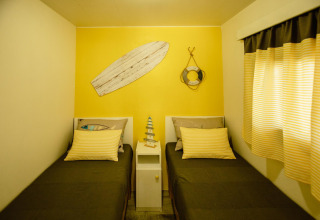 Kamer met twee eenpersoonsbedden in Miramar Mobile Home CINQUE TERRE, Spanje, gele muur, stranddecoratie.