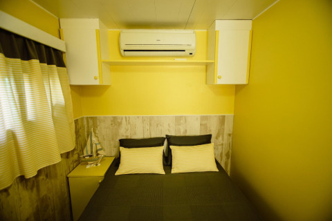 Kleine slaapkamer in Miramar Mobile home CINQUE TERRE, Spanje, met geel interieur en airconditioning.