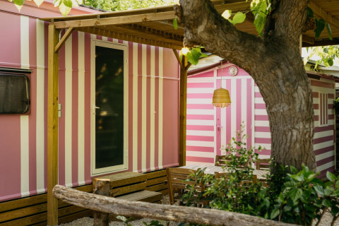 Miramar Mobile home CINQUE TERRE in Spanje met roze-witte strepen, zithoek buiten, grote boom.