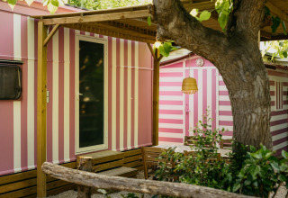 Miramar Mobile home CINQUE TERRE in Spanje met roze-witte strepen, zithoek buiten, grote boom.