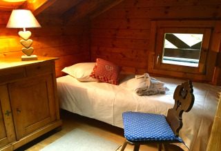 Gezellige slaapkamer met houten wanden, eenpersoonsbed, hartjeslamp en raam in chalet Remschweiler, Frankrijk.