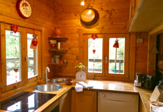 Cuisine chaleureuse en bois décorée de cœurs, chalet Remschweiler, en France, pleine de lumière.