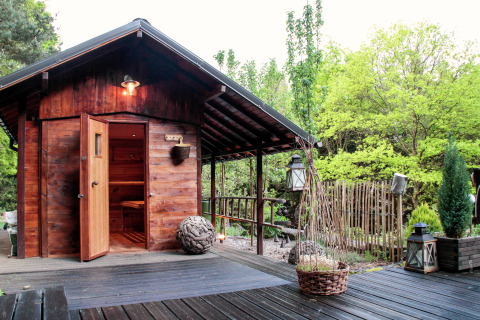 Chalet en bois chaleureux « Remschweiler » en France, entouré de verdure et d’arbres, porte entrouverte.