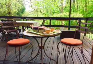Terrasse extérieure au chalet Remschweiler en France, avec chaises, table, confitures et forêt verdoyante.