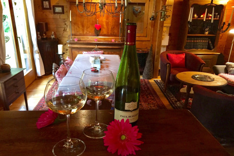 Twee wijnglazen en een fles wijn op een houten tafel in een gezellig chalet in Remschweiler, Frankrijk.