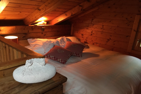 Sfeervolle slaapkamer in chalet Remschweiler, Frankrijk, met houten interieur, bed en sierkussens.