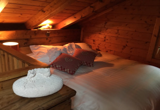 Sfeervolle slaapkamer in chalet Remschweiler, Frankrijk, met houten interieur, bed en sierkussens.