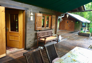 Uitzicht op chalet Remschweiler in Frankrijk met houten terras, bank, open ramen en groene omgeving.