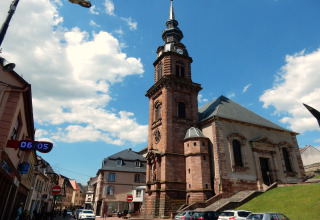 Photo d'une église historique à Remschweiler, France, sous un ciel bleu parsemé de quelques nuages.
