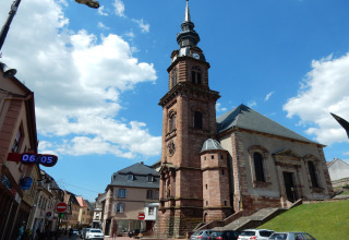Foto van een historische kerk in Remschweiler, Frankrijk, met blauwe lucht en enkele wolken.