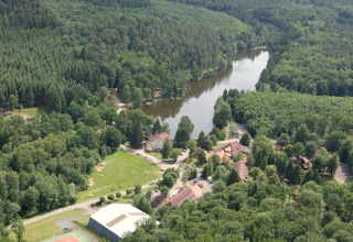 Vue aérienne du chalet Remschweiler en France, entouré de forêt dense et d’une rivière sinueuse paisible.