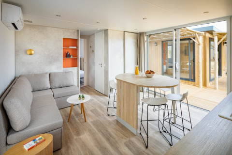 Moderne opholdsstue og spiseområde på Beach Resort «Agde 5» i Frankrig med sofa, bord og udendørs terrasse.