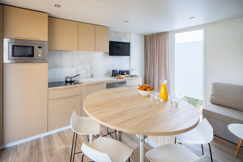 Moderne køkken og spiseplads i en lodge på Beach Resort «Agde 5» i Frankrig med morgenmad på bordet.
