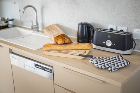 Moderne køkkenbord i Beach Resort «Agde 5» med brød, brødrister, elkedel og opvaskemaskine.