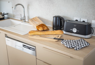 Moderne køkkenbord i Beach Resort «Agde 5» med brød, brødrister, elkedel og opvaskemaskine.