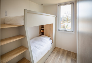 Moderne værelse med køjeseng, trægulv og stort vindue på Beach Resort «Agde 5» i Frankrig.