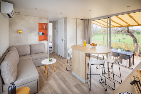 Moderne mobilhome Beach Resort Agde 4 i Frankrig med stue, spisebord og udsigt til terrasse og have.