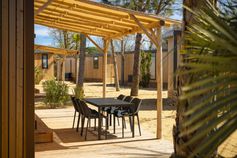 Udendørs terrasse med sort bord og stole under træpergola ved Beach Resort «Agde 4» i Frankrig.
