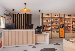 Modern reception og butik med træindretning og snacks på hylderne i Beach Resort Agde 2, Frankrig.