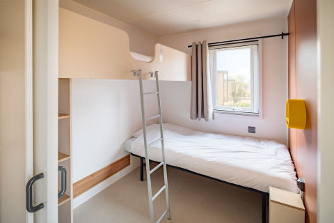 Moderne mobil home soveværelse med køjeseng, stige og vindue på Beach Resort Agde 2 i Frankrig.