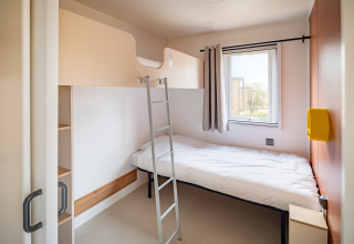 Moderne mobil home soveværelse med køjeseng, stige og vindue på Beach Resort Agde 2 i Frankrig.
