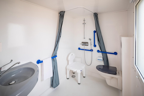Handicapvenligt badeværelse i mobilhome Beach Resort «Agde 2» i Frankrig med bruser og støttehåndtag.