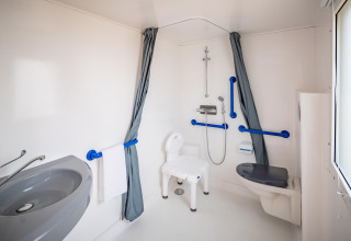 Handicapvenligt badeværelse i mobilhome Beach Resort «Agde 2» i Frankrig med bruser og støttehåndtag.
