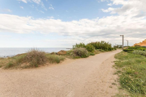 Sti ved stranden ved Beach Resort «Agde 2» i Frankrig, omgivet af grønne buske og udsigt til havet.