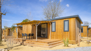 Mobil-home moderne en bois avec terrasse aménagée au Beach Resort Agde 1 sous un ciel ensoleillé.