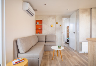 Moderne stue i mobilhome Beach Resort «Agde 1» i Frankrig med hjørnesofa, bord og hyggelig indretning.