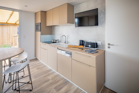 Moderne mobilhome-køkken ved Beach Resort Agde 1 i Frankrig med beige skabe og spiseplads.