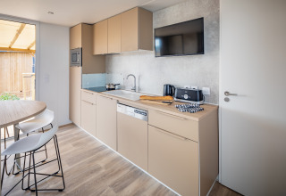 Moderne mobilhome-køkken ved Beach Resort Agde 1 i Frankrig med beige skabe og spiseplads.