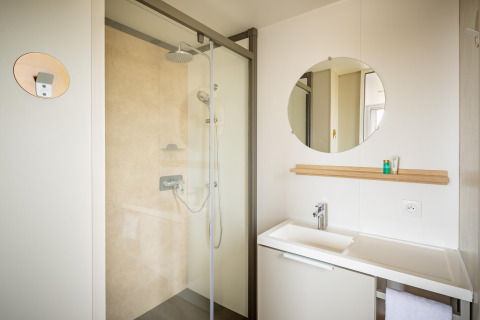 Moderne badeværelse i Beach Resort Agde 1 mobilhome med brusekabine, spejl og håndvask i Frankrig.