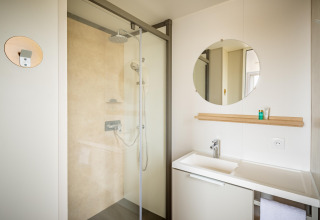 Moderne badeværelse i Beach Resort Agde 1 mobilhome med brusekabine, spejl og håndvask i Frankrig.