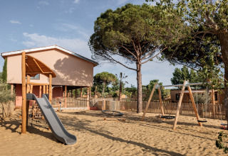 Legeplads med rutsjebane og gynger i sandet foran mobilhjemmet Beach Resort «Agde 1» i Frankrig.