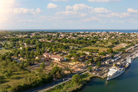 Luftfoto af Beach Resort Agde 1 i Frankrig med udsigt over boliger, havn og kystlinje i baggrunden.