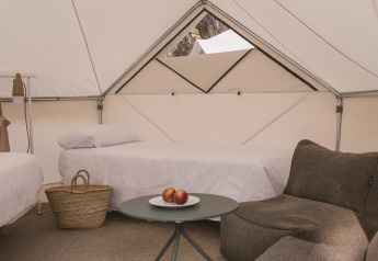 Interno della Bell Tent Plus al Wecamp Santa Cristina in Spagna con letti, divano e arredo essenziale.
