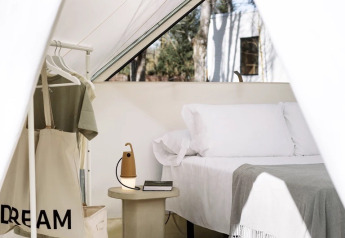 Interno della Bell Tent Plus al Wecamp Santa Cristina in Spagna con letto, attaccapanni e tavolino.
