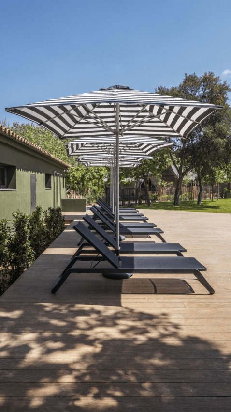 Ligstoelen en zwart-witte parasols op terras bij Cabin Tent in wecamp Santa Cristina, Spanje.