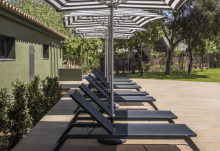 Ligstoelen en zwart-witte parasols op terras bij Cabin Tent in wecamp Santa Cristina, Spanje.