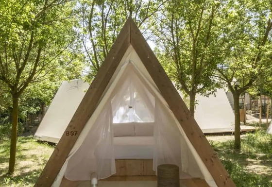 Safari Cabin Tent op houten terras in een groene bosomgeving, met open ingang en wit interieur.