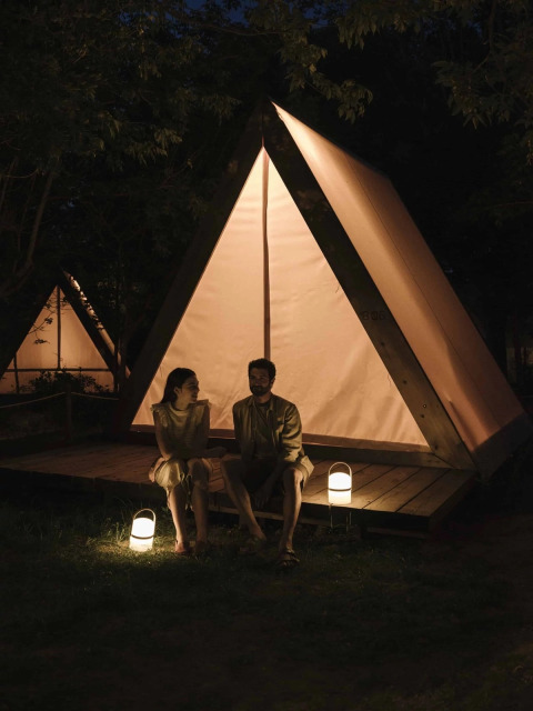 Twee personen zitten bij een verlichte safaritent in het donker bij Wecamp Santa Cristina, Spanje.