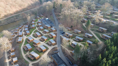 Luftaufnahme des Ferienparks Hameau de la Semois in Belgisch-Luxemburg mit vielen Holzhütten.